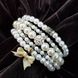 Браслет в 5 рядів на струні з пластиковими намистинами імітації перлів діаметром 4, 6 і 8 мм, довжина обхвату близько 16 см, колір білий